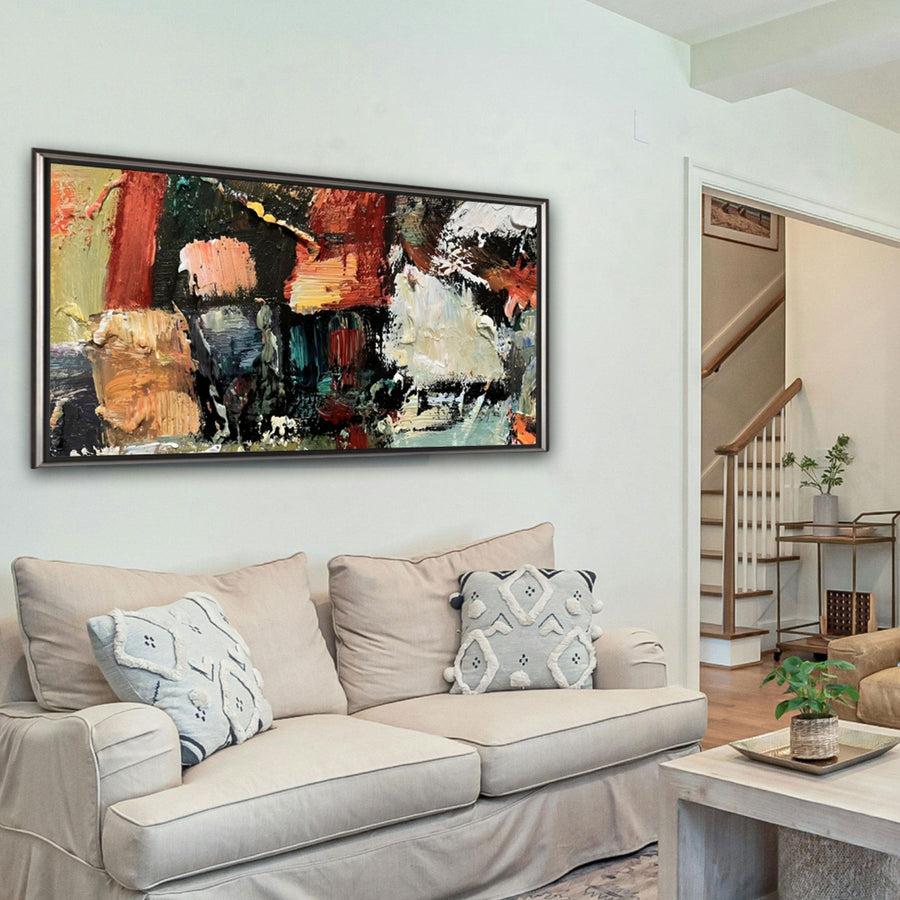 Living room with a beige sofa, abstract painting on the wall, and a staircase in the background.