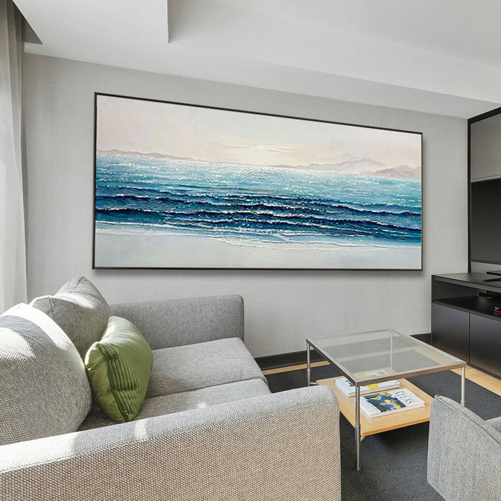 Living room with a large ocean painting on the wall, gray sofa, and glass coffee table.