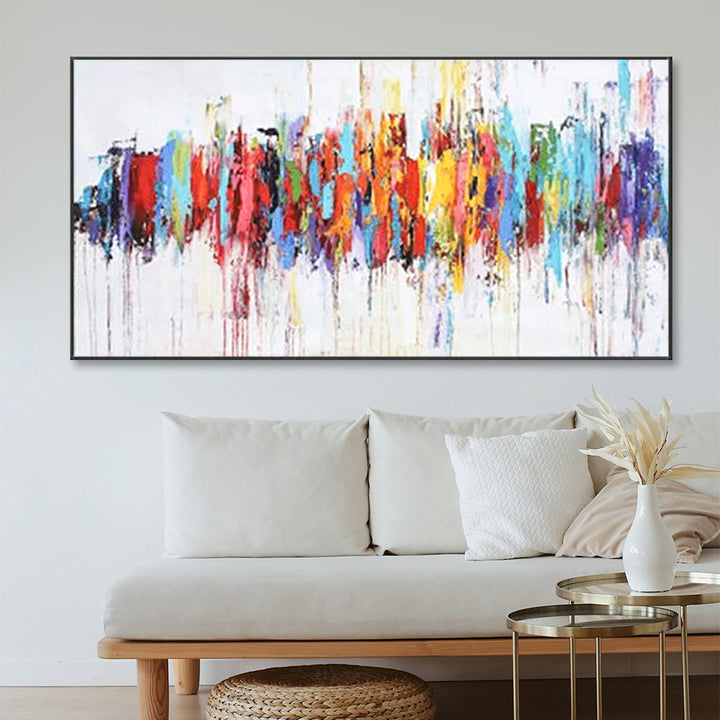 Colorful abstract painting on a wall above a white sofa with decorative elements.