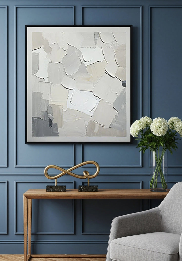 Abstract art piece on a blue paneled wall with a console table and chair.