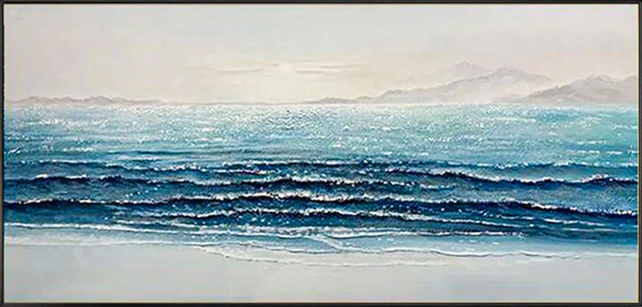 Panoramic view of a beach with ocean waves and distant mountains.